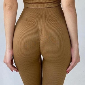 Peut inclure: Un ensemble de haut et de leggings sans couture côtelés de couleur marron. Le haut est de style dos nageur et les leggings sont taille haute.
