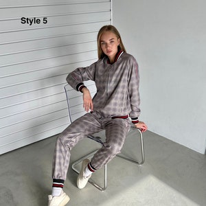 May include: A gray and white plaid tracksuit with red and white stripes on the sleeves and legs. The model is wearing the tracksuit and sitting on a clear chair. The text "Style 5" is visible in the top left corner of the image.