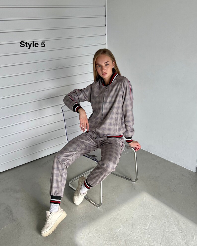May include: A gray and white plaid tracksuit with red and white stripes on the sleeves and legs. The model is wearing the tracksuit and sitting on a clear chair. The text "Style 5" is visible in the top left corner of the image.