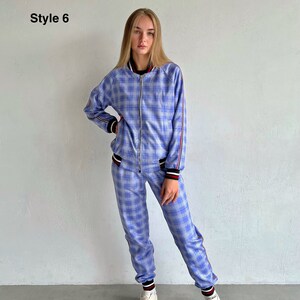May include: A blue and white plaid tracksuit with red and black trim. The jacket has a zipper closure and the pants have a drawstring waist. The model is wearing white sneakers.