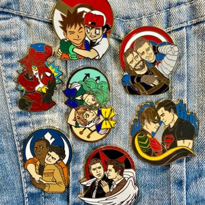 Peut inclure: Plusieurs épingles émaillées colorées représentant des personnages de dessins animés et de bandes dessinées en duo. Les épingles, sur un fond en jean, présentent des personnages comme Spider-Man et des personnages de Pokémon.