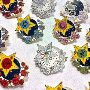 Può includere: Un set di dieci spille smaltate con diversi disegni di stelle e lune con accenti floreali. Ogni spilla ha un contorno dorato e uno sfondo di colore diverso. Le spille sono perfette per aggiungere un tocco di fantasia ai tuoi vestiti, borse o altri accessori.