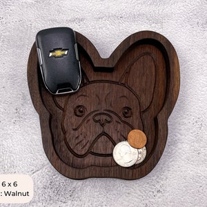 May include: A wooden tray shaped like a French Bulldog, with a black car key and coins inside. The tray is 6 inches by 6 inches and made of walnut wood. Size: 6 x 6 Material: Walnut
