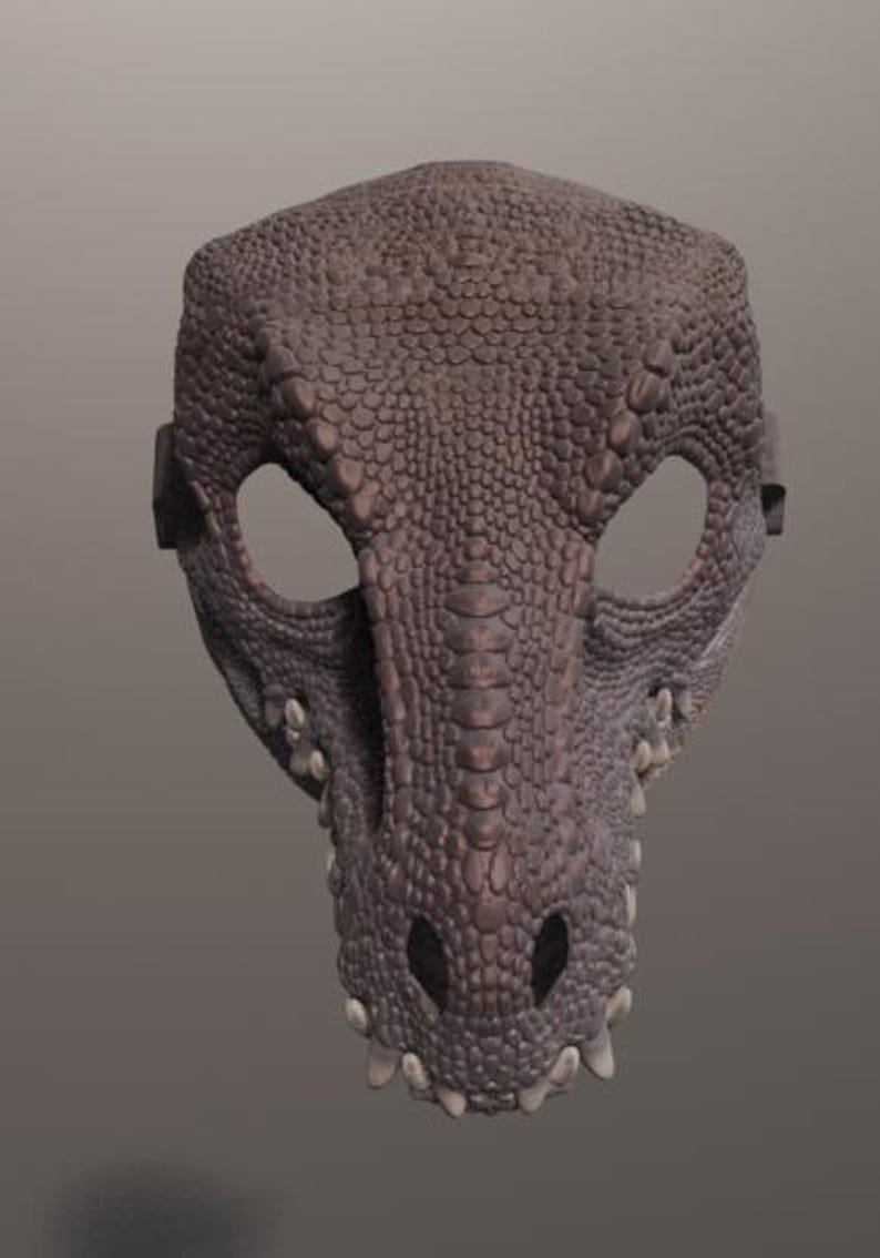 May include: A detailed, brown dragon mask with a textured, scaly surface. The mask features large eye openings, a prominent snout, and small, pointed teeth. The mask is designed to be worn, with straps on the sides.