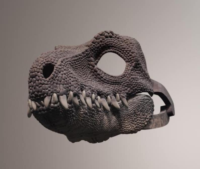 May include: A detailed, textured dinosaur mask in shades of gray and brown. The mask features a realistic design with visible teeth and eye openings, suggesting a costume or prop for themed events.