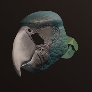 Puede incluir: Una máscara de loro impresa en 3D con un esquema de color verde y azul. La máscara tiene un pico y plumas detalladas.