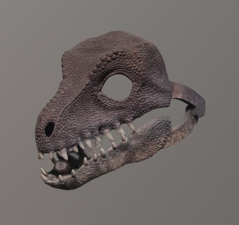 May include: A detailed, textured dinosaur skull mask in shades of brown and gray. The mask features a large eye opening, sharp teeth, and a textured surface, suggesting a realistic design. The mask is designed to be worn.