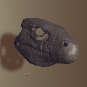 May include: A grey, textured, 3D printed model of a lizard head. The model has a detailed, scaly texture and a slightly open mouth.