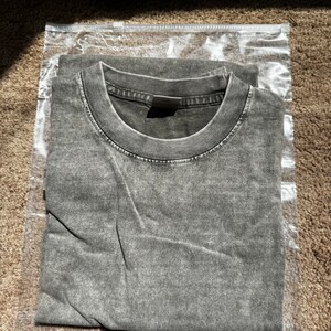 May include: A folded gray t-shirt in a clear plastic bag.