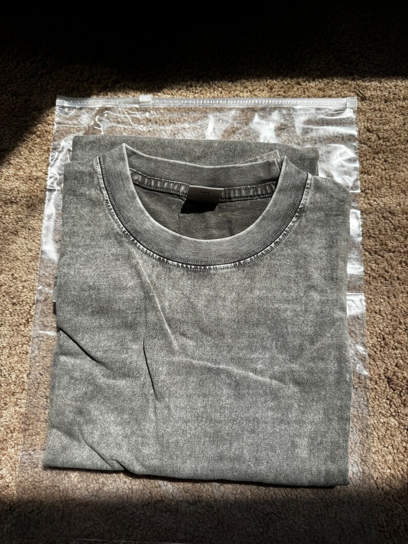 May include: A folded gray t-shirt in a clear plastic bag.