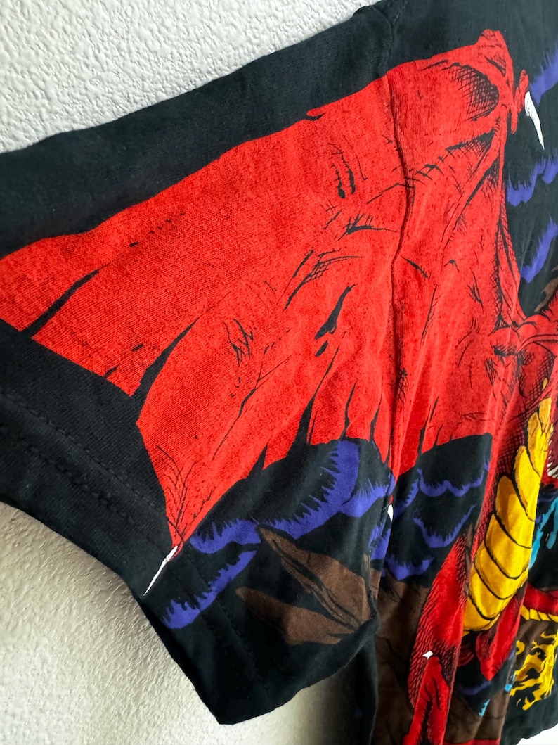 May include: Black t-shirt with a colorful graphic print of a dragon with red, yellow, blue, and brown details.