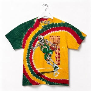Puede incluir: Camiseta teñida con un esqueleto jugando al baloncesto. La camiseta presenta los colores de la bandera lituana: verde, rojo y amarillo. El texto "TEAM LITHUANIA BASKETBALL 96" está impreso en la parte delantera.