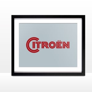 May include: A framed print with a red and white logo for the car company Citroën. The logo is a stylized wordmark with the name of the company in a bold, sans-serif font.