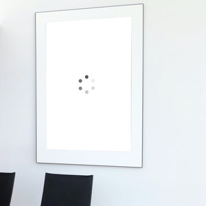May include: A white picture frame with a loading icon in the centre. The frame is hanging on a white wall.