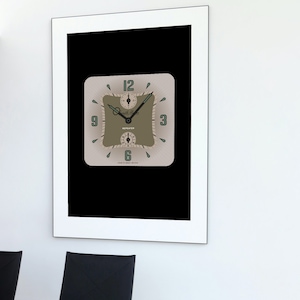 May include: A framed black and white print of a square clock with a beige face and green accents. The clock face has black Roman numerals and a black second hand. The clock is labeled "Regulator" and "Made in Great Britain".