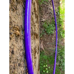 Peut inclure: Gros plan d'un cerceau d'exercice violet, &eacute;galement appel&eacute; hula hoop, avec une surface textur&eacute;e. Le cerceau est appuy&eacute; contre un mur rugueux et textur&eacute;.
