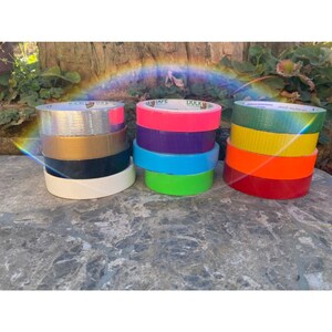 Peut inclure: Assortiment de rouleaux de ruban adh&eacute;sif de diff&eacute;rentes couleurs, dont argent, or, noir, blanc, rose, violet, bleu, vert, orange et rouge.