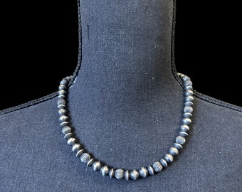 May include: A silver necklace with round beads, each bead has a textured design.