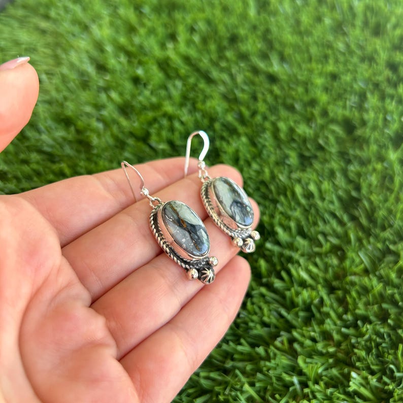 May include: A pair of silver earrings with oval-shaped black and white stones. The stones have a marbled pattern.