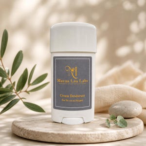 May include: A white cream deodorant stick with a gray label featuring gold text and a logo. The label reads "Mauna Loa Labs Cream Deodorant" and the net weight is 2.2 oz (63 gm). The deodorant is on a stone platform.