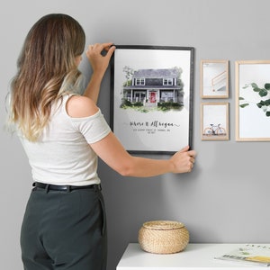 woman hanging a framed custom home portrait