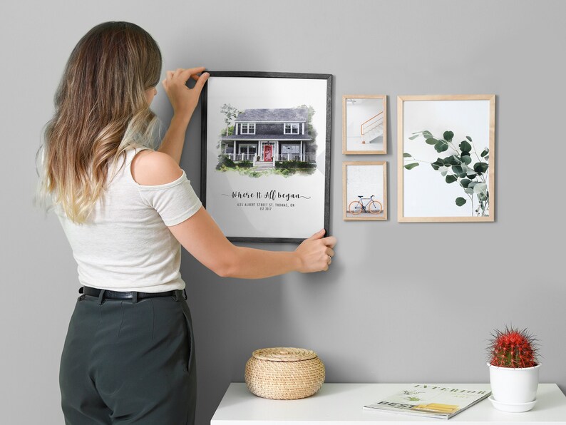 woman hanging a framed custom home portrait