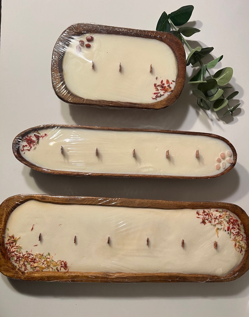 Pode incluir: Tr&ecirc;s tigelas de madeira com velas brancas e flores secas. As tigelas s&atilde;o de tamanhos e formas diferentes. As velas est&atilde;o todas acesas.