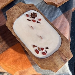 Pode incluir: Uma bandeja de madeira com uma vela branca e detalhes decorativos vermelhos e marrons. A vela &eacute; cercada por pequenos peda&ccedil;os de madeira vermelhos e marrons e uma estrela de anis.