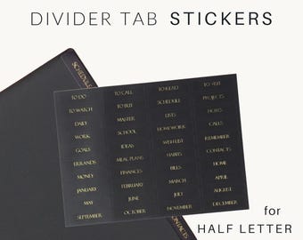 May include: A sheet of black rectangular divider tab stickers with gold text featuring labels such as TO DO, TO CALL, TO READ, TO VISIT, TO WATCH, TO BUY, SCHEDULE, PROJECTS, DAILY, MASTER, LISTS, NOTES, WORK, SCHOOL, HOMEWORK, CALLS, GOALS, IDEAS, WISH LIST, REMEMBER, ERRANDS, MEAL PLANS, HABITS, CONTACTS, MONEY, FINANCES, BILLS, HOME, JANUARY, FEBRUARY, MARCH, APRIL, MAY, JUNE, JULY, AUGUST, SEPTEMBER, OCTOBER, NOVEMBER, DECEMBER.