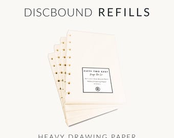 May include: A stack of off-white discbound paper refills with punched edges. The top sheet features a black rectangular label reading FIFTY TWO EAST, Design Your Life, 5.5" x 8.5" Disc Bound Refill, Heavy Drawing Paper, 50 Sheets. Text reads DISCBOUND REFILLS.