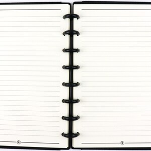 May include: An open disc-bound notebook with cream-colored lined paper and black covers. The center features a black plastic disc spine binding. A yellow wooden pencil with a pink eraser is attached to the right side of the black cover edge.