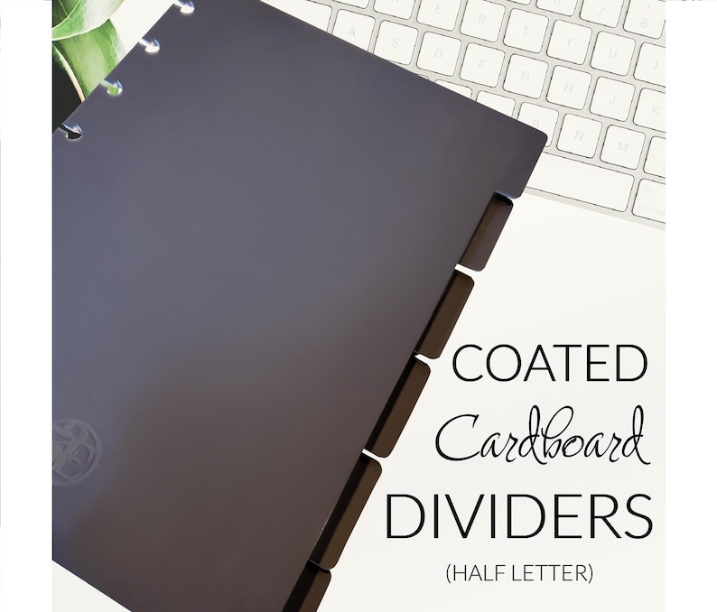 May include: Grey coated cardboard dividers for a half-letter size planner. The dividers have tabs on the right side and a circular logo on the front.