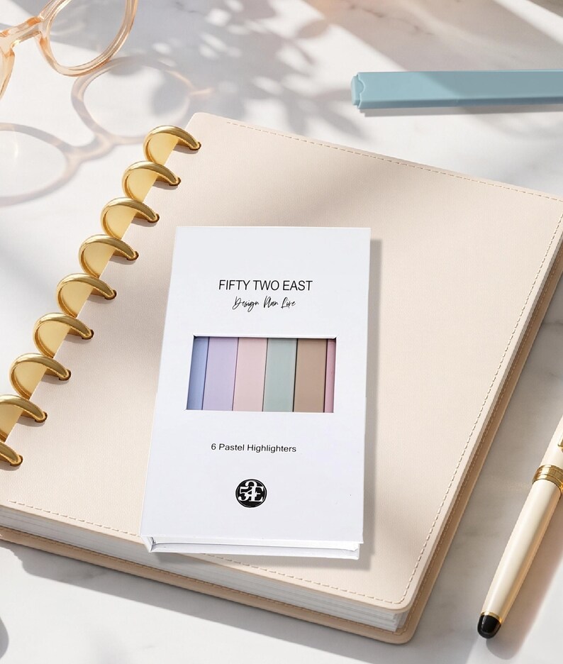 May include: A white rectangular box containing six pastel highlighters in blue, purple, pink, green, and brown. The box features the text FIFTY TWO EAST, Design Plan Life, 6 Pastel Highlighters, and a circular logo with the letters 52E.