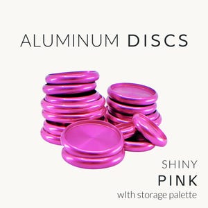 May include: A collection of shiny pink aluminum discs stacked in two piles, with the text ALUMINUM DISCS at the top and SHINY PINK with storage palette at the bottom. The discs have a metallic finish and a circular shape with a raised outer rim.