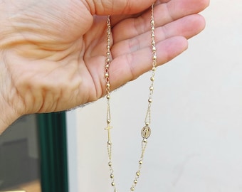 May include: A gold chain necklace with a small cross and a round pendant featuring a religious image.