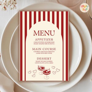 以下が含まれることがあります： クリーム色の背景に赤い縦縞模様のメニューカード。「MENU」の文字が上部にあり、前菜、メインコース、デザートのオプションが続きます。デザートセクションには、ハート型のクッキーとチョコレート溶岩ケーキがあります。カクテルグラスとハートが描かれています。