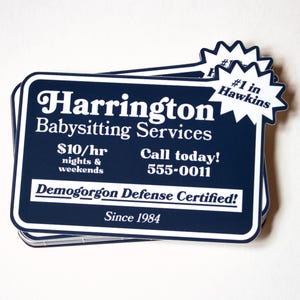 Puede incluir: Una tarjeta de visita azul y blanca con el texto "Harrington Babysitting Services" y "#1 en Hawkins". La tarjeta también incluye el texto "10 €/h noches y fines de semana", "¡Llame hoy! 555-0011", y "Demogorgon Defense Certified! Desde 1984".