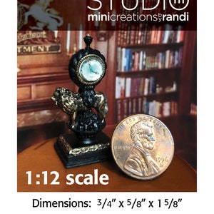 May include: A miniature black lion mantle clock with gold accents and a white clock face. The clock is 3/4 inches wide, 5/8 inches deep, and 1 5/8 inches tall. The clock is 1:12 scale and is not a toy for small children.