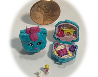 May include: A collection of miniature toys, including a blue cat-shaped case with a pink bow, a teal case with a bedroom scene, a tiny doll, and a small white cat figurine. A US penny is included for size reference.