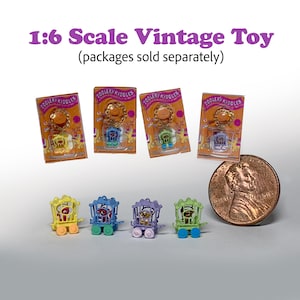 Könnte beinhalten: Eine Sammlung von Miniatur-Vintage-ZooLery-Kiddles-Spielzeugen, jeweils in einer anderen Farbe, darunter Gelb, Blau, Lila und Grün. Die Spielzeuge werden mit ihrer Originalverpackung und einem Cent zur Größenbestimmung gezeigt. Der Text "1:6 Scale Vintage Toy" ist sichtbar.