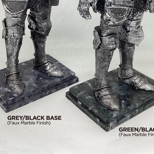 May include: Two silver knight figurines with detailed armor, standing on square bases with a faux marble finish. The base on the left is grey and black, while the base on the right is green and black. The text "GREY/BLACK BASE (Faux Marble Finish)" is below the left figurine, and the text "GREEN/BLACK BASE (Faux Marble Finish)" is below the right figurine.