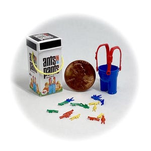 Op de afbeelding: Een vintage bordspel genaamd "Ants in the Pants" met een rood-wit-blauw kleurenschema. Het spel bevat een blauwe plastic emmer met rode banden, een doos met een geel deksel en een set kleurrijke plastic mieren.