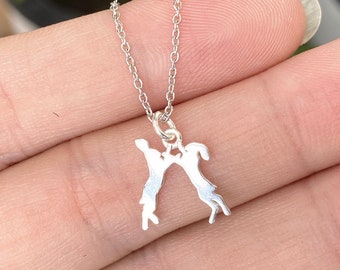 May include: A silver necklace with a pendant featuring two figures holding hands, silhouetted against a white background.