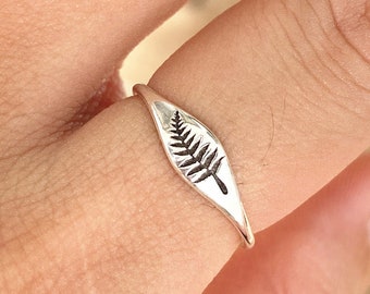 Könnte beinhalten: Ein silberner Ring mit einem Farnblatt-Design.