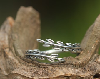 May include: A silver ring with a delicate design of intertwined branches and leaves. The ring is adjustable and can be worn on any finger.