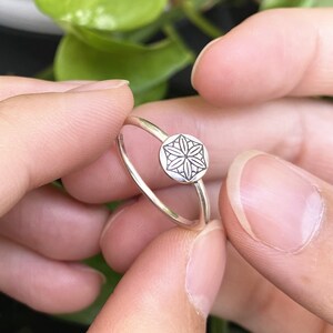 Op de afbeelding: Een zilveren ring met een delicaat, gegraveerd bloemetjesontwerp. De ring is simpel en elegant, perfect voor dagelijks gebruik.