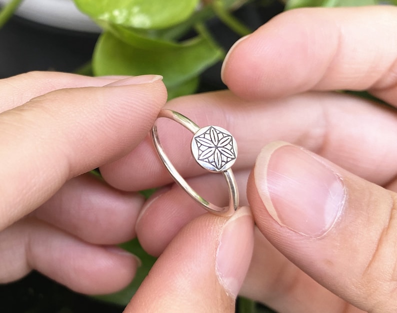 Op de afbeelding: Een zilveren ring met een delicaat, gegraveerd bloemetjesontwerp. De ring is simpel en elegant, perfect voor dagelijks gebruik.