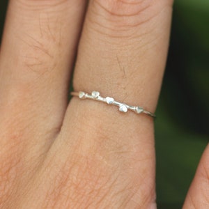 K&ouml;nnte beinhalten: Ein silberner Ring mit einem zarten Design aus f&uuml;nf kleinen Herzen.