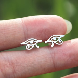 Peut inclure: Une paire de boucles d'oreilles en argent avec un motif d'œil détaillé. Les boucles d'oreilles sont petites et délicates, et seraient un excellent cadeau pour quelqu'un qui aime les bijoux uniques.