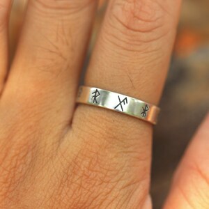Könnte beinhalten: Ein silberner Ring mit drei darauf gravierten nordischen Runen. Die Runen sind "R", "X" und "P".